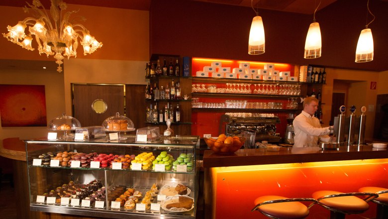 Cafe Helmut & Helmut, © schwarz-koenig.at Innenansicht eines Cafés mit Theke, Barhocker und Gebäckvitrine.