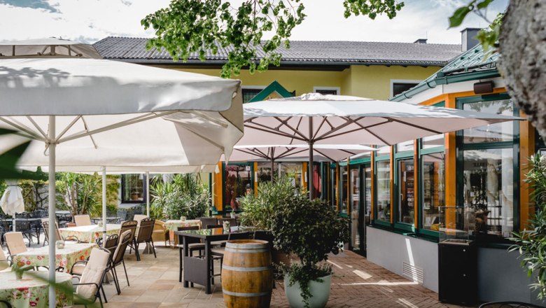 Außenbereich eines Restaurants mit Tischen, Stühlen und Sonnenschirmen.