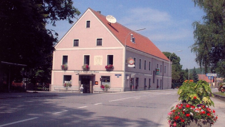 A traditional inn on a street corner decorated with flowers.
