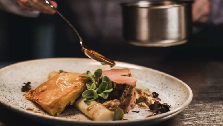 A plate of veal medallions, asparagus and puff pastry, garnished with sauce and herbs.