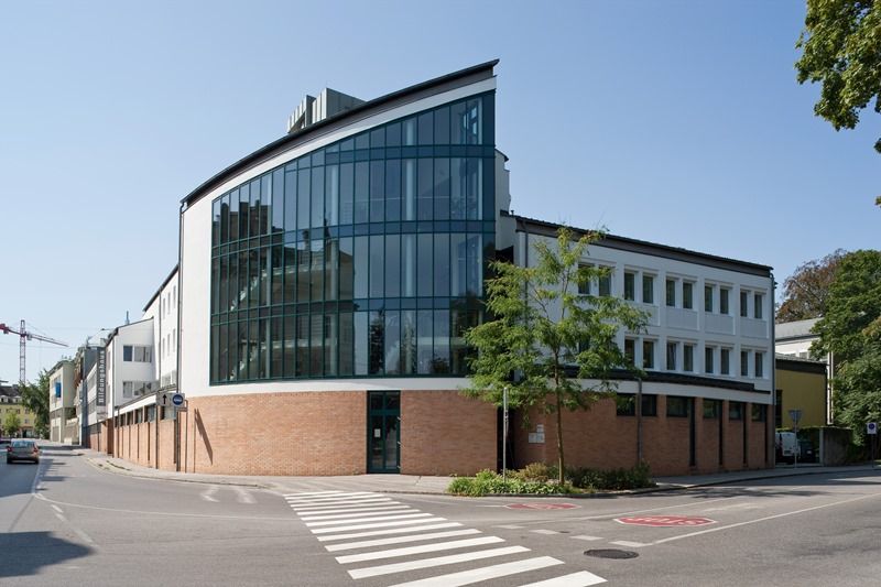Modernes Gebäude mit Glasfassade und Ziegelmauerwerk an einer Straßenecke.