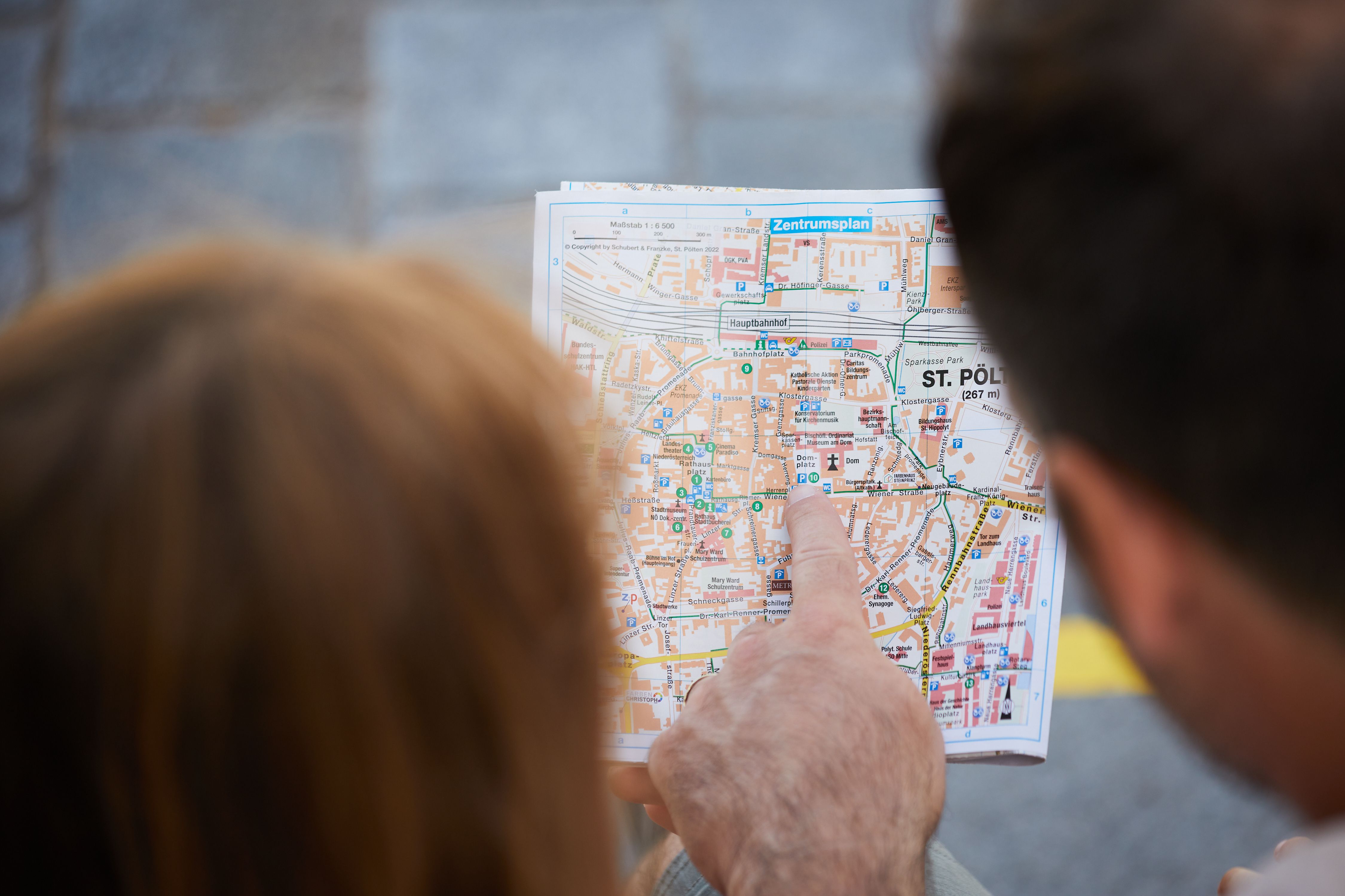 Zwei Personen sehen sich den Stadtplan an und einer zeigt auf den Domplatz.