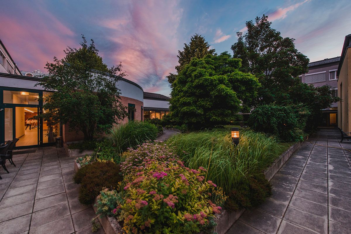 Innenhof des Bildungshauses St. Hippolyt mit Garten und Abendhimmel.