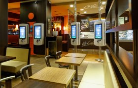 Interior view of a McDonald's restaurant with ordering terminals and seating areas.