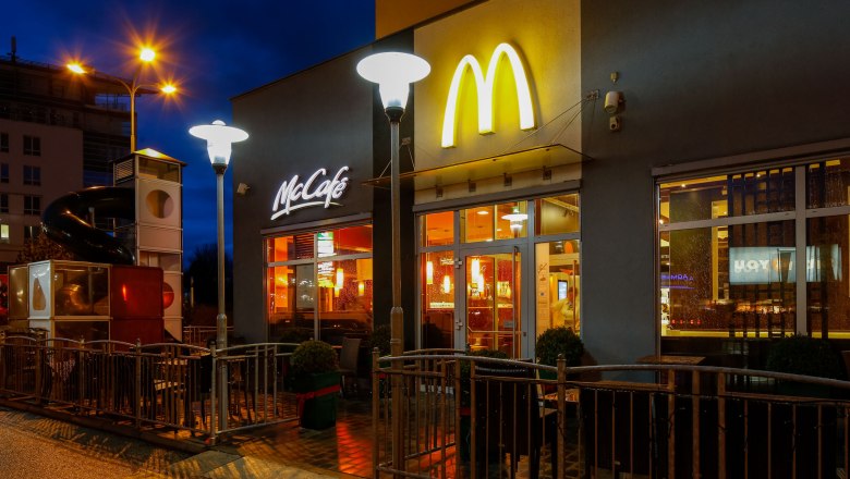 Exterior view of a McDonald's restaurant at night with illuminated logo and McCaf&eacute; sign.