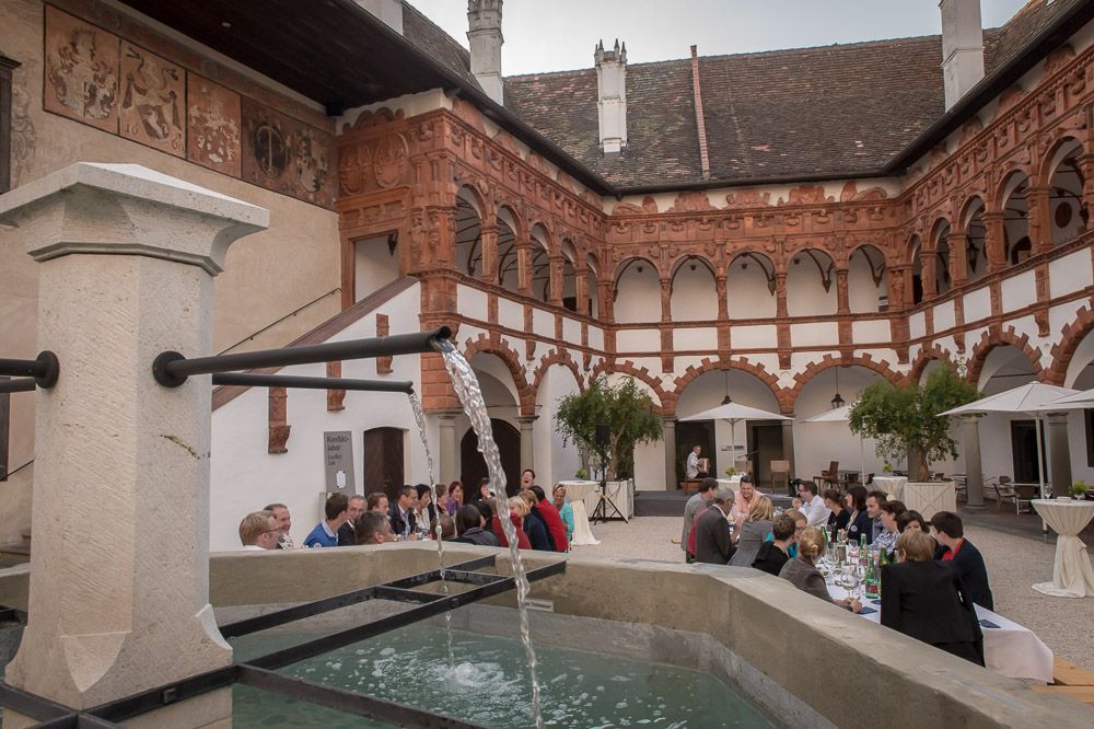 Innenhof mit Brunnen, speisenden Gästen und eindrucksvoller Architektur an den Innenwänden.