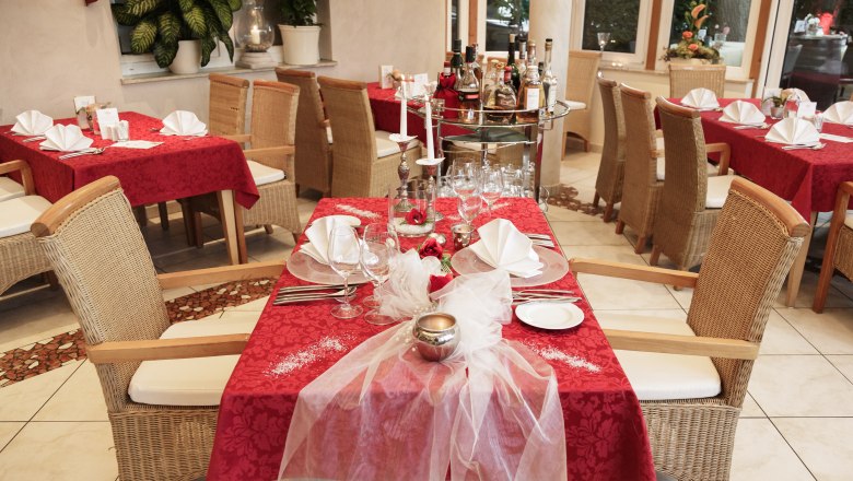 Elegantes Restaurant mit roten Tischdecken und gedeckten Tischen.