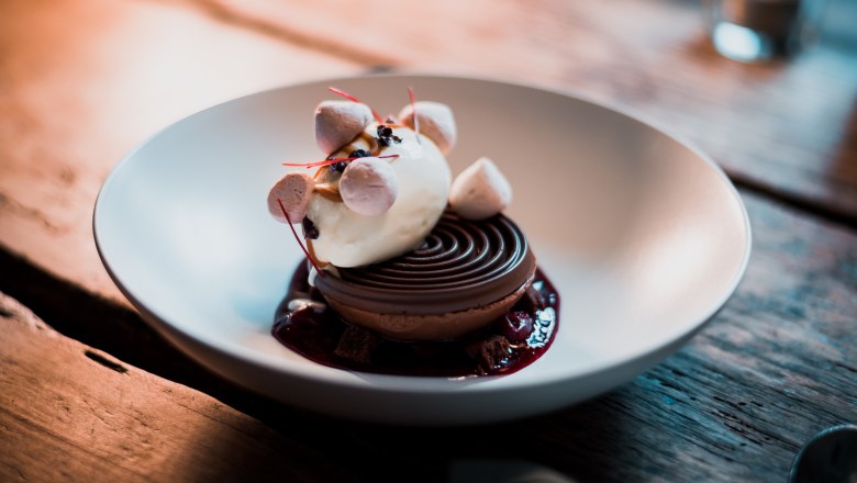 Ein Dessert mit Eis, Mousse und Crumble in einer Schale serviert.