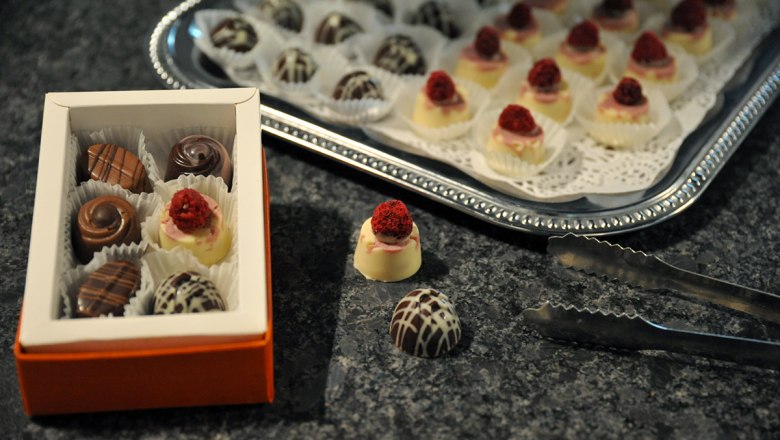 Eine Schachtel Pralinen und ein Tablett mit Pralinen auf einem Tisch.