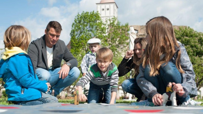 Lachende Kinder und ihre Eltern spielen gemeinsam beim bunten Familienfest.