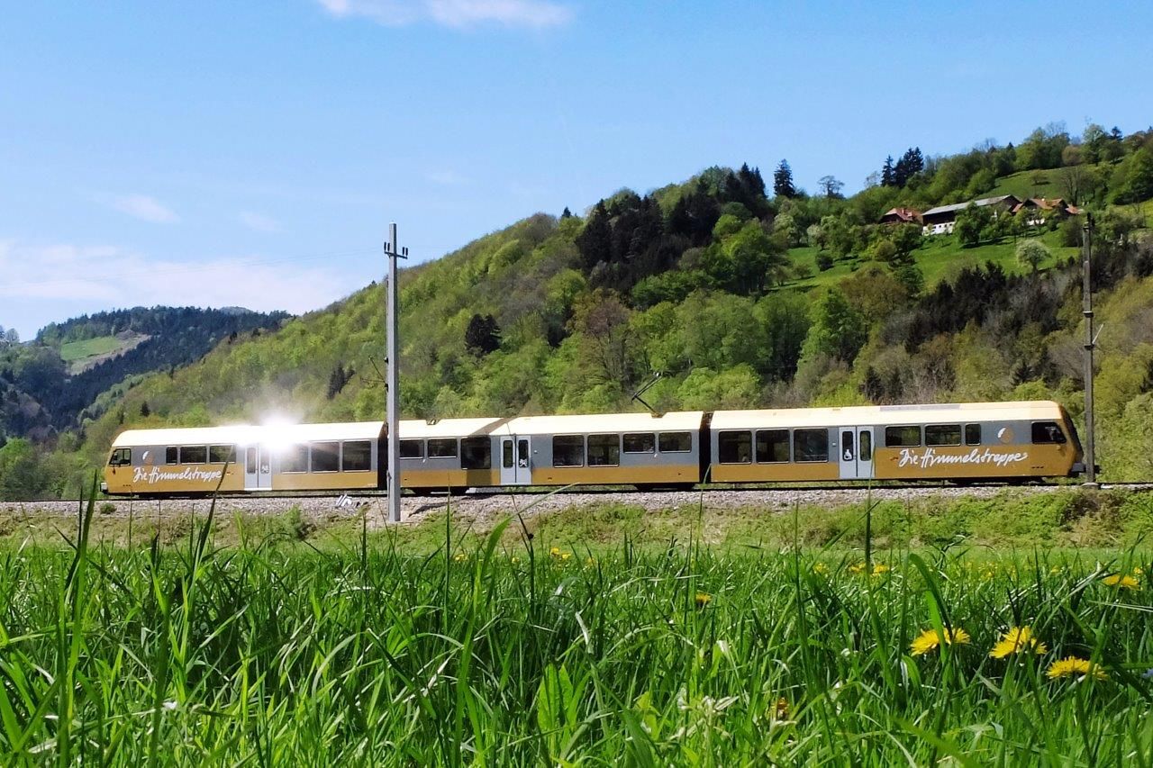 Die Himmelstreppe fährt durch eine grüne, sanft hügelige Landschaft.