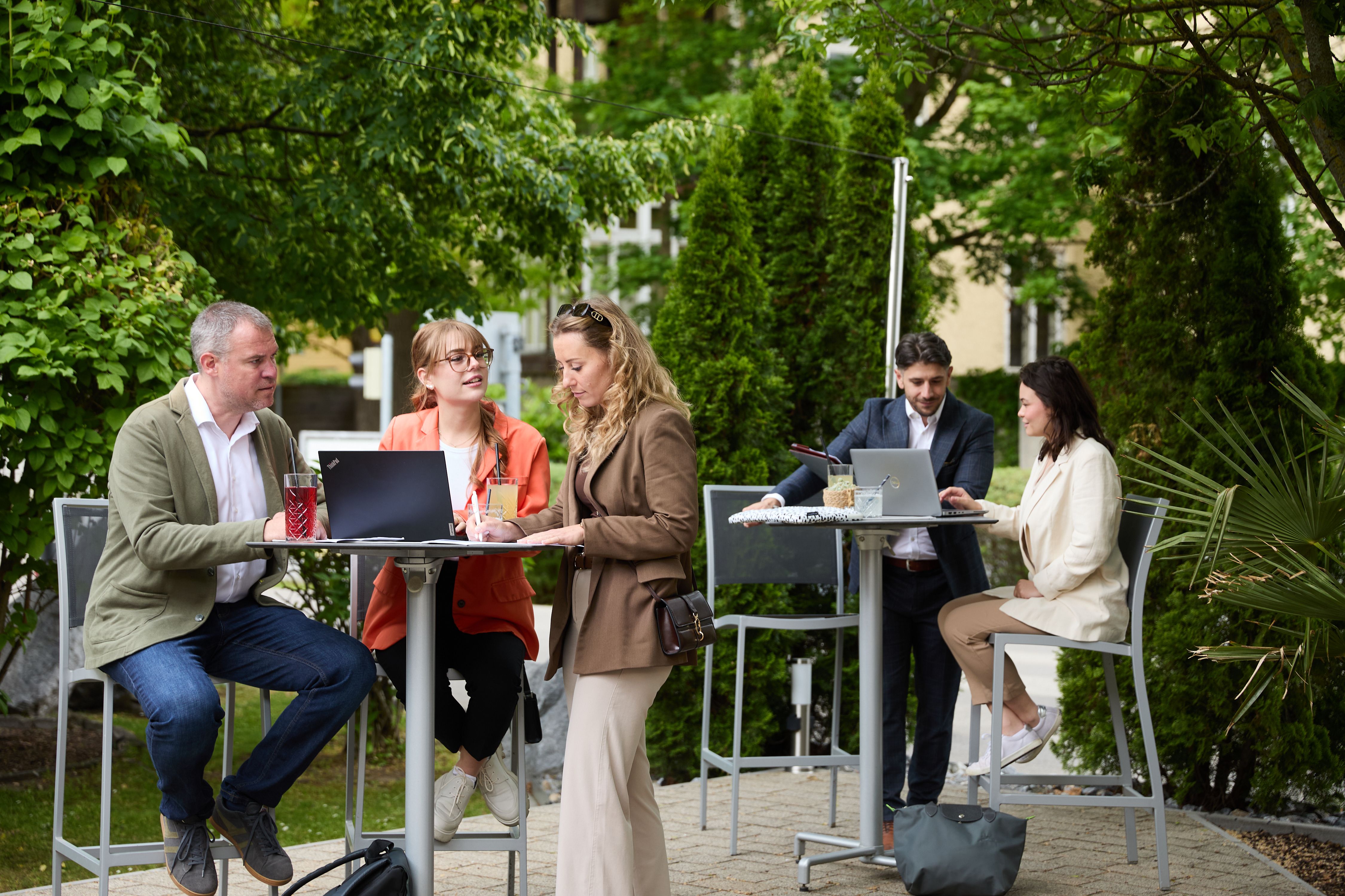 Geschäftsleute arbeiten gemeinsam im Garten des Cityhotels