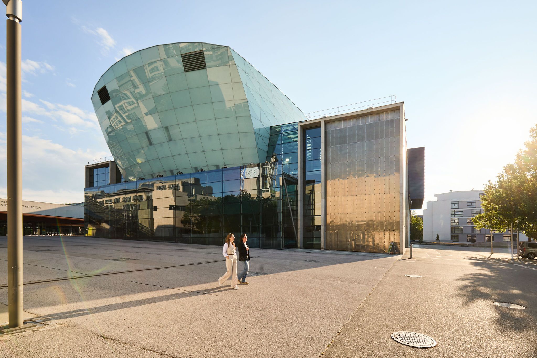 Zwei Damen spazieren an dem Festspielhaus im Kulturbezirk vorbei.