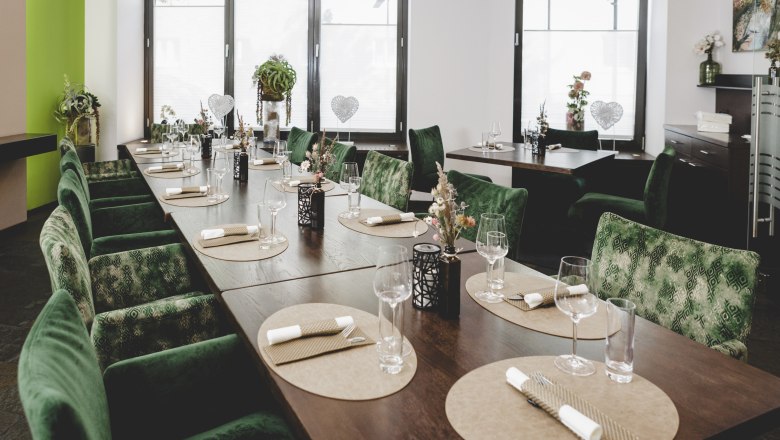 Elegant restaurant with green chairs and table setting.