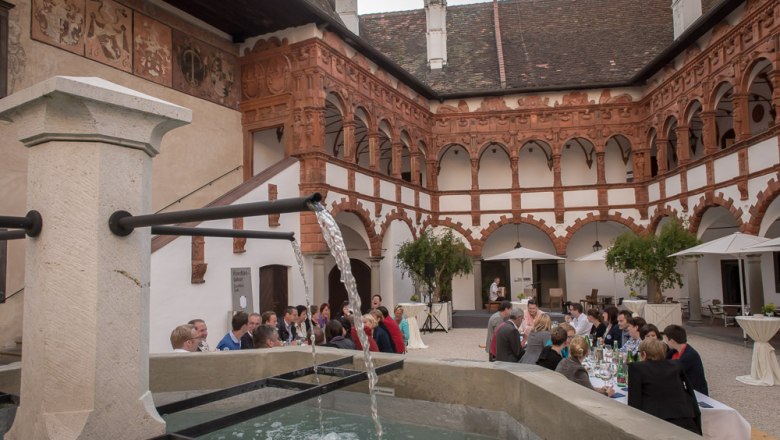 Innenhof mit Brunnen, speisenden G&auml;sten und eindrucksvoller Architektur an den Innenw&auml;nden.