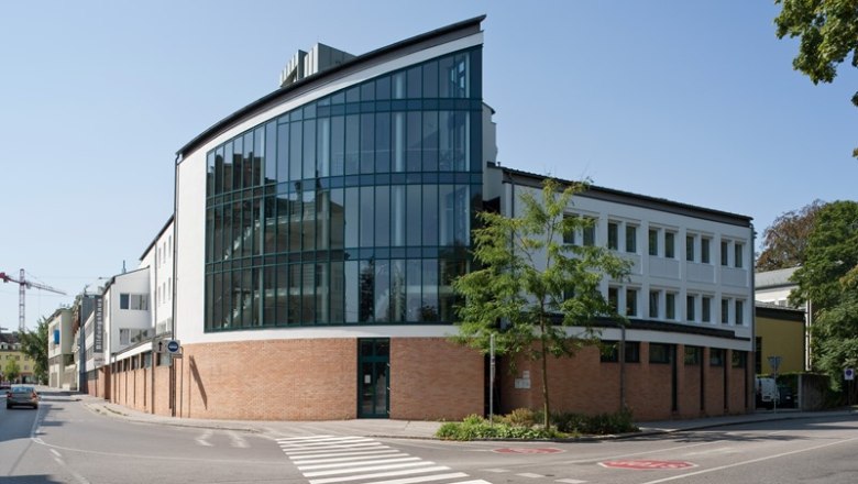 Modern building with glass fa&ccedil;ade and brickwork on a street corner.