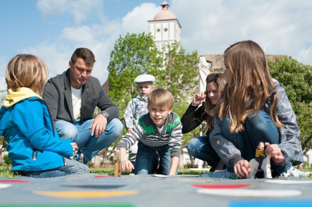 Lachende Kinder und ihre Eltern spielen gemeinsam beim bunten Familienfest.