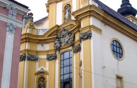 Baroque church with yellow façade and statues.