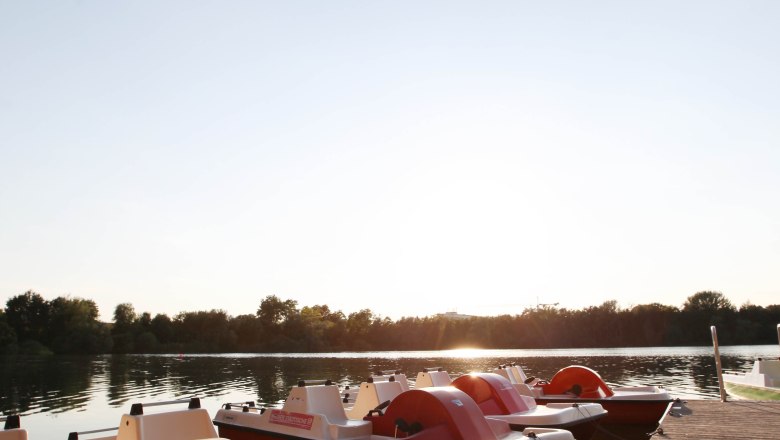 Tretboote am Steg bei Sonnenuntergang.