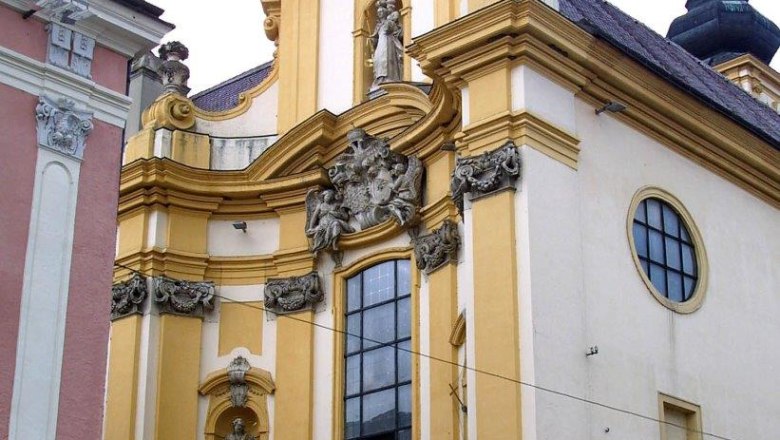 Barocke Kirche mit gelber Fassade und Statuen.