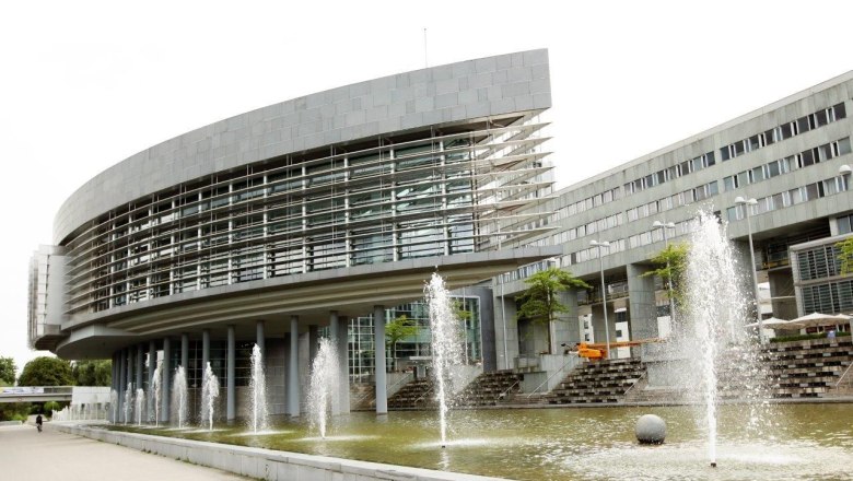 Modernes Gebäude mit Glasfassade und Springbrunnen im Vordergrund.