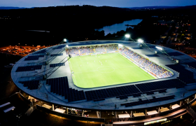 Luftaufnahme eines beleuchteten Fu&szlig;ballstadions bei Nacht.